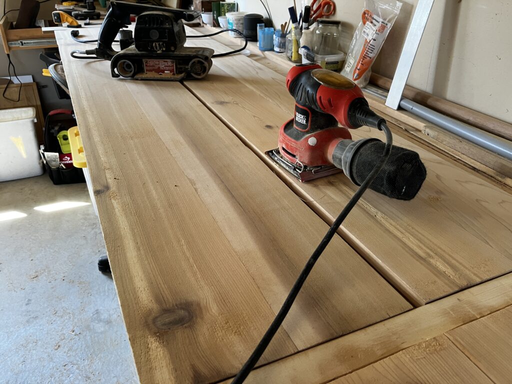 two sanders and some cedar boards on a work bench