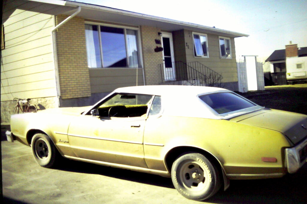 A tan Mercury in a driveway.